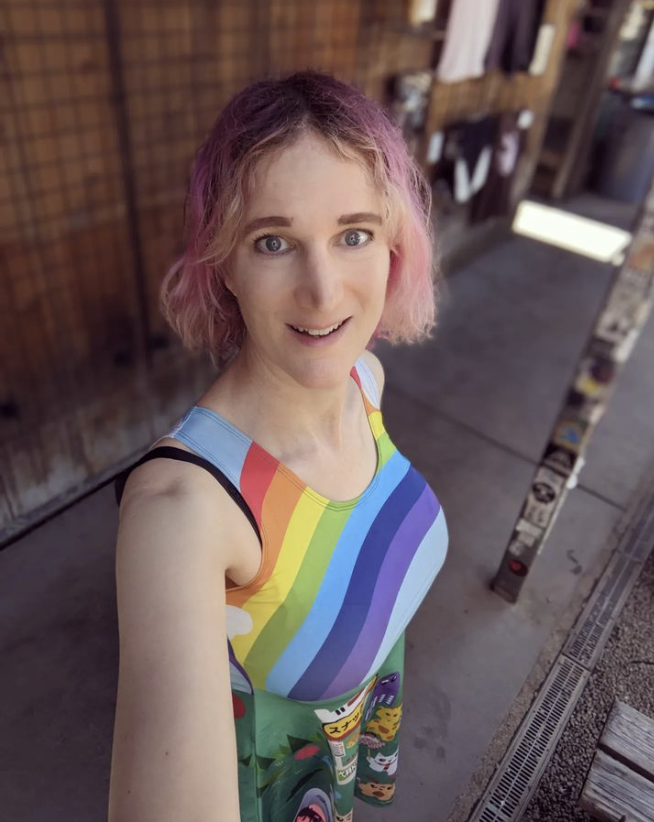 Autora Charlie Jane Anders com as cores do arco-íris, simbolizando a bandeira LGBTQIAP+.